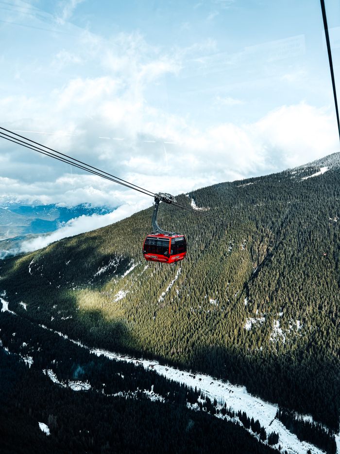 Red cable car traveling over snow-covered mountains amidst a stunning winter landscape.
