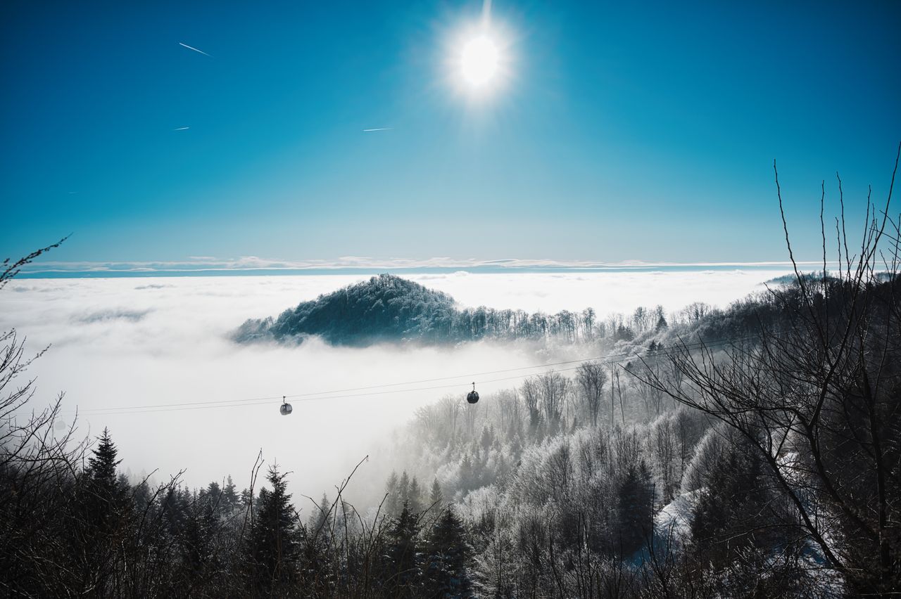 Breathtaking winter landscape featuring cable cars over snowy mountains and a bright sunlit sky.
