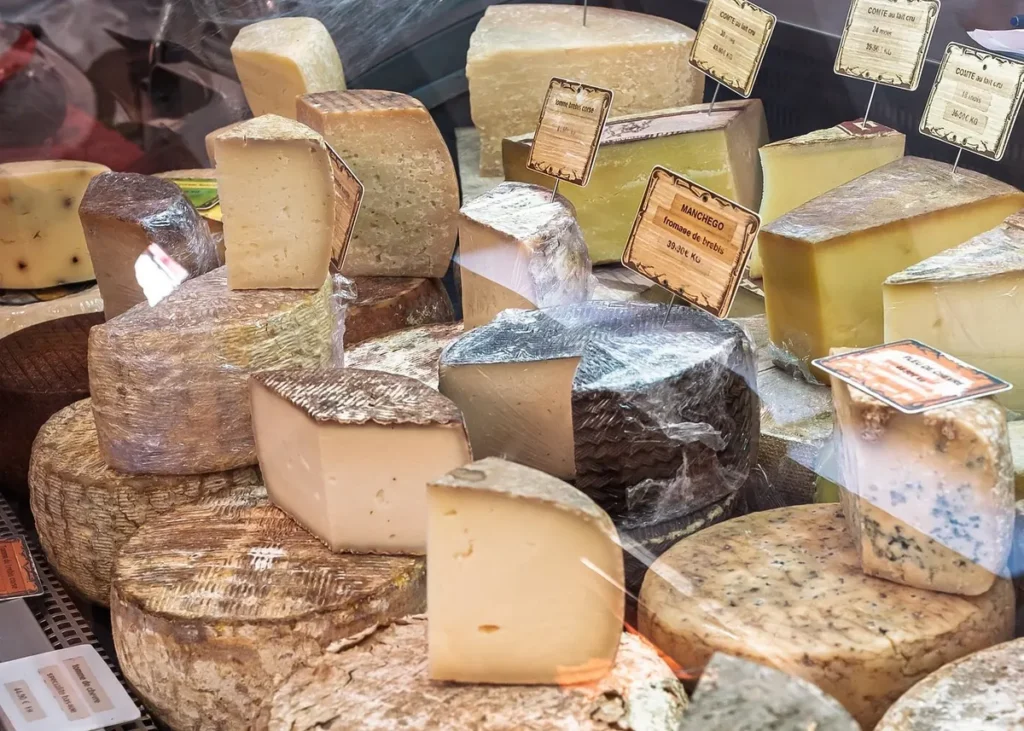 Selection of artisan French cheeses displayed at a traditional cheese shop, including Comté and aged regional varieties