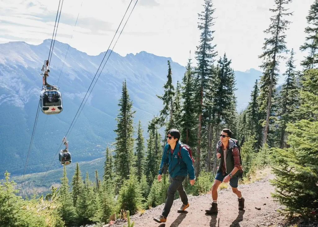 Hikers walking along a mountain trail beside the Banff Gondola overlooking the Canadian Rockies