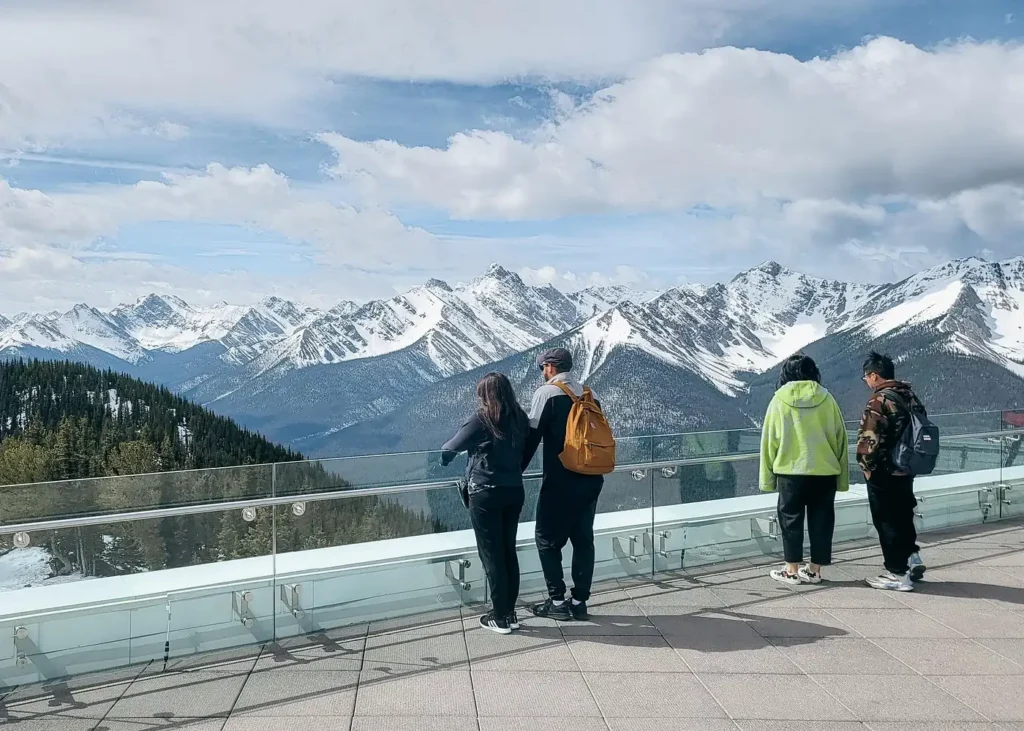 Visitors enjoying panoramic views of the snow-capped Canadian Rockies from the Banff Gondola summit observation deck