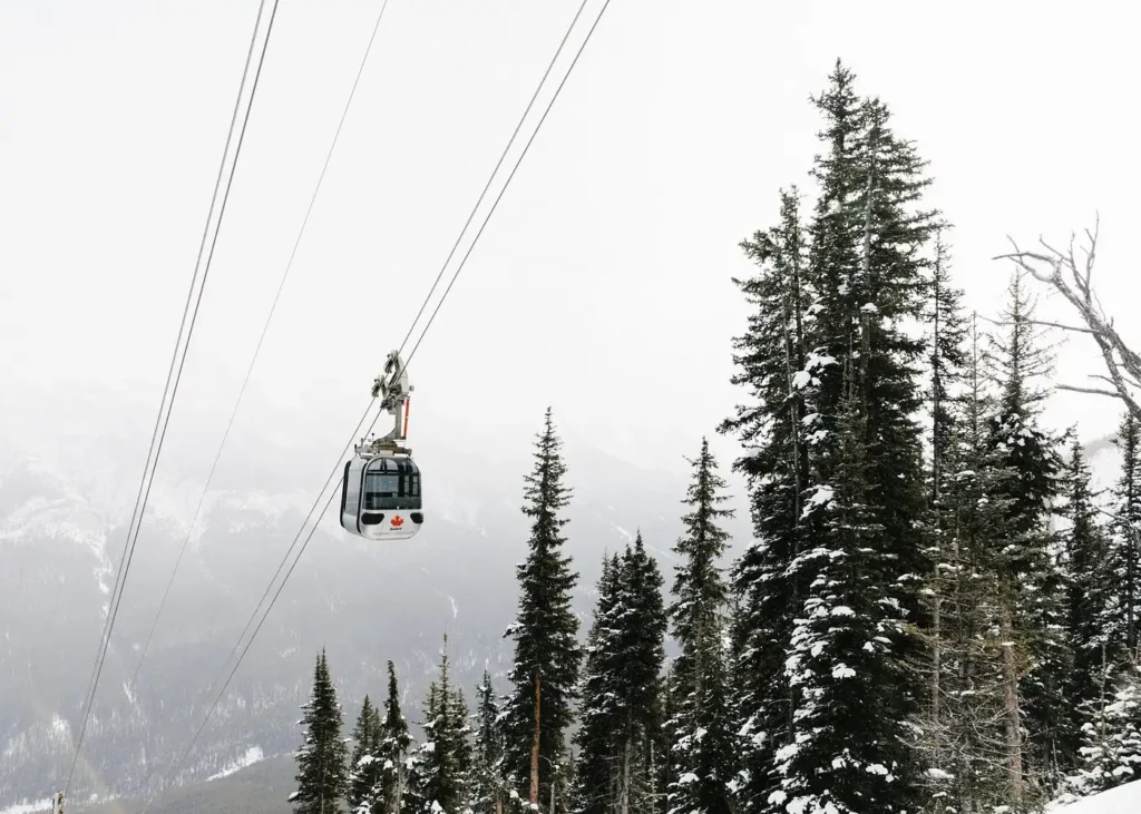 Banff Gondola cable car above snow-covered evergreen forests in Banff National Park, Canadian Rockies