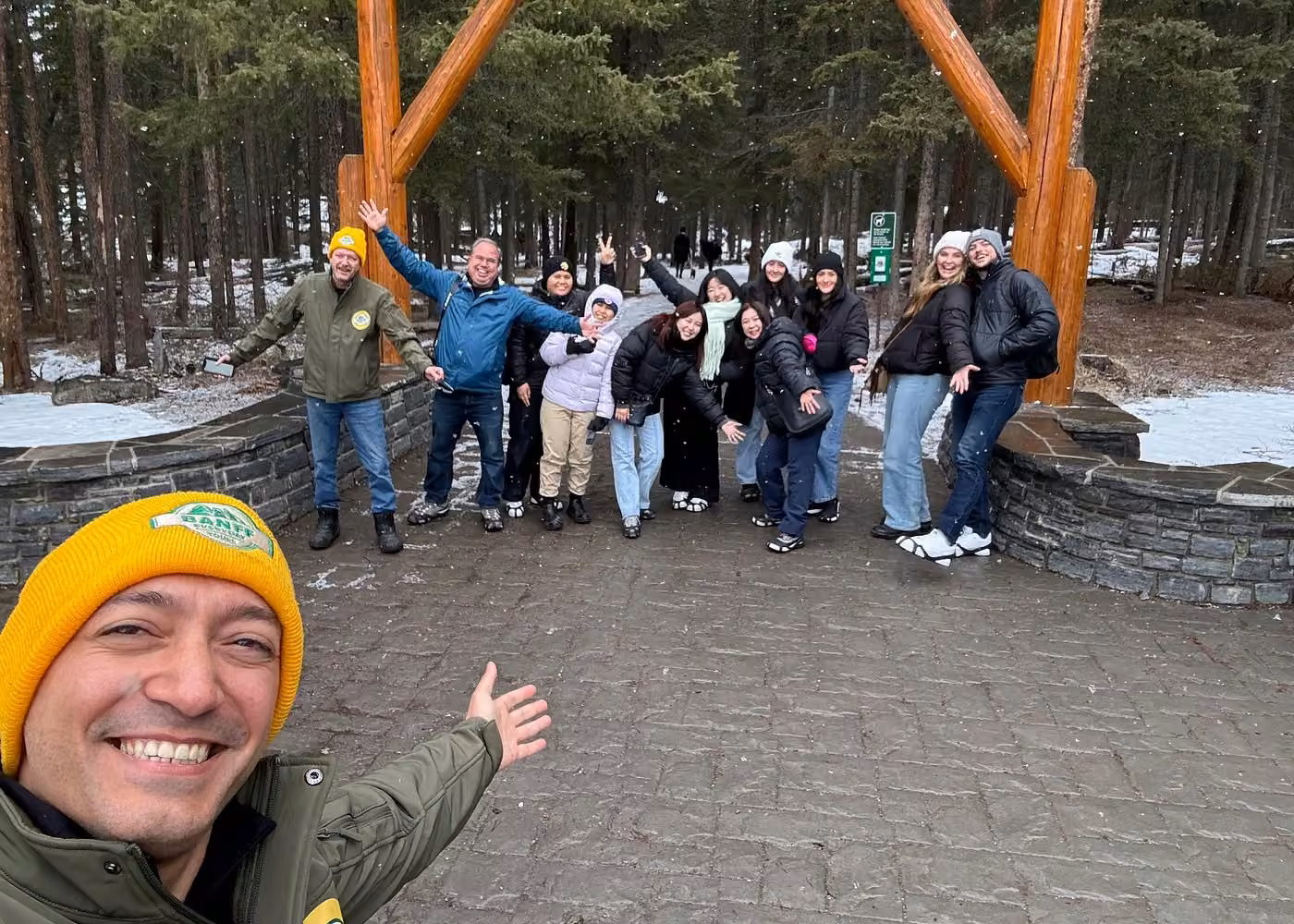 Happy group of travelers posing with their guide during a winter sightseeing tour in Banff National Park