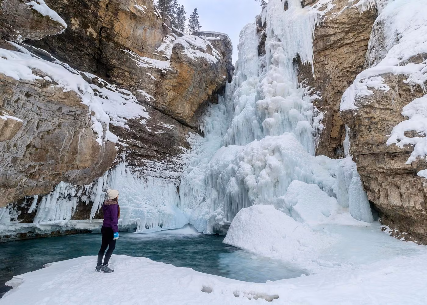 Visitor admiring a spectacular frozen waterfall at Johnston Canyon in Banff National Park during winter