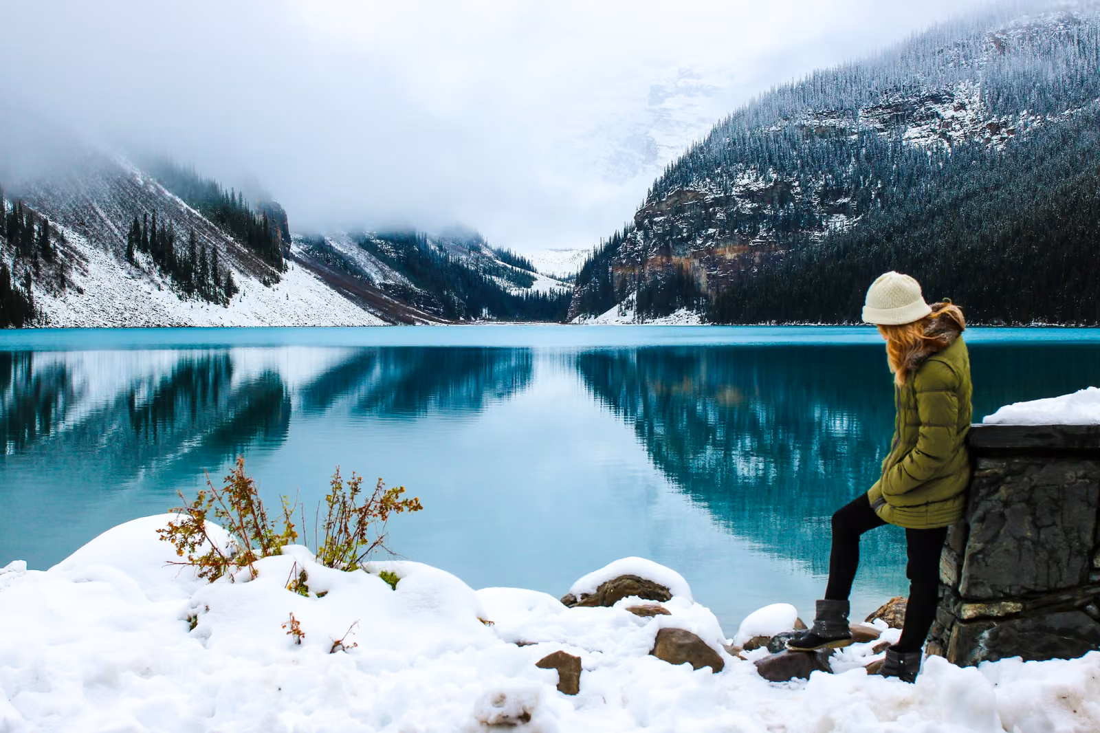Woman enjoying the turquoise waters of Lake Louise surrounded by snow-covered mountains in Banff National Park