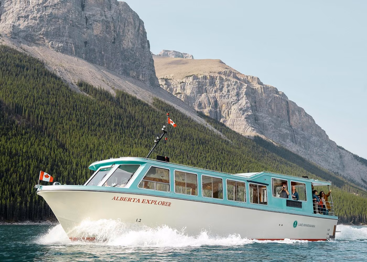 Lake Minnewanka sightseeing cruise boat sailing across the lake with Rocky Mountains in the background