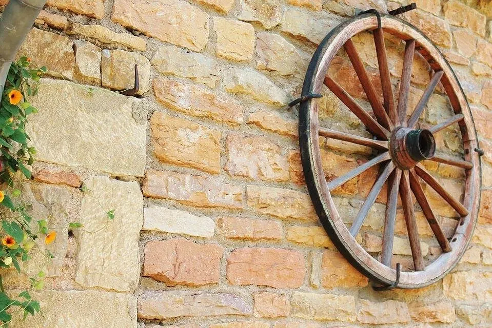 Rustic wooden wagon wheel on a golden stone wall in the Beaujolais region of France