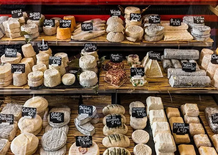 Selection of artisanal French cheeses displayed on wooden shelves with handwritten price labels