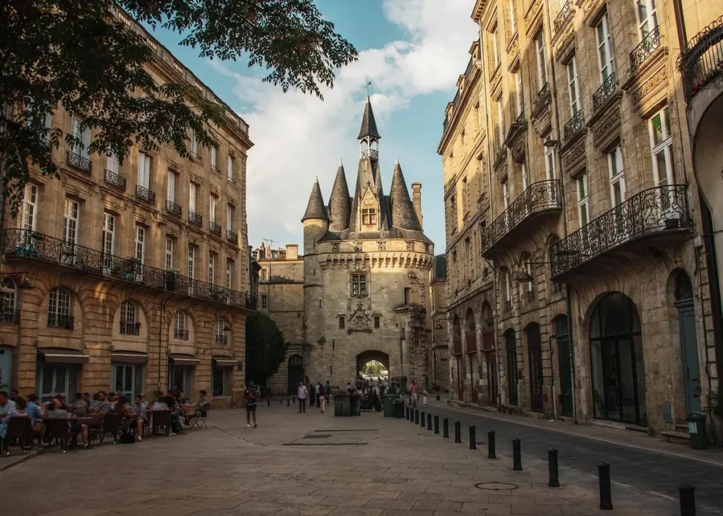 Porte Cailhau medieval gateway surrounded by historic stone buildings and outdoor cafes in Bordeaux