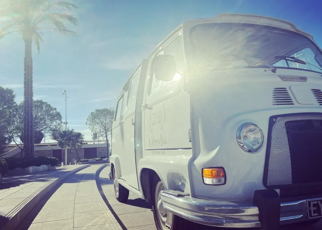 Classic white French vintage sightseeing bus parked along a palm-lined street in Cannes