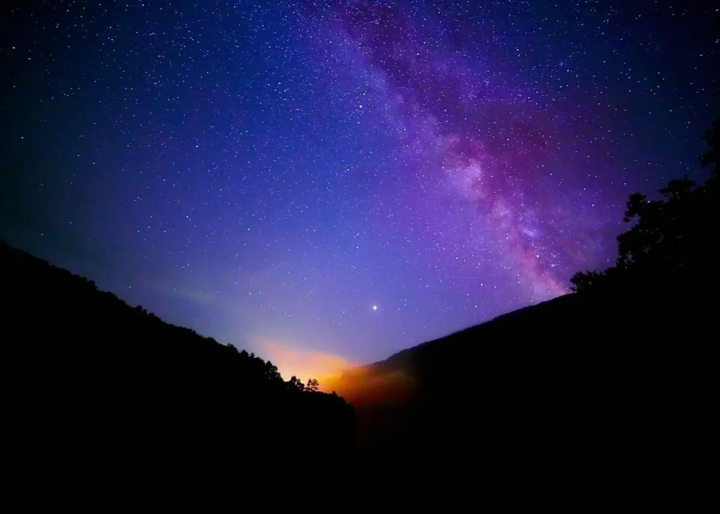 Star-filled night sky with the Milky Way above dark mountain silhouettes during a desert stargazing experience