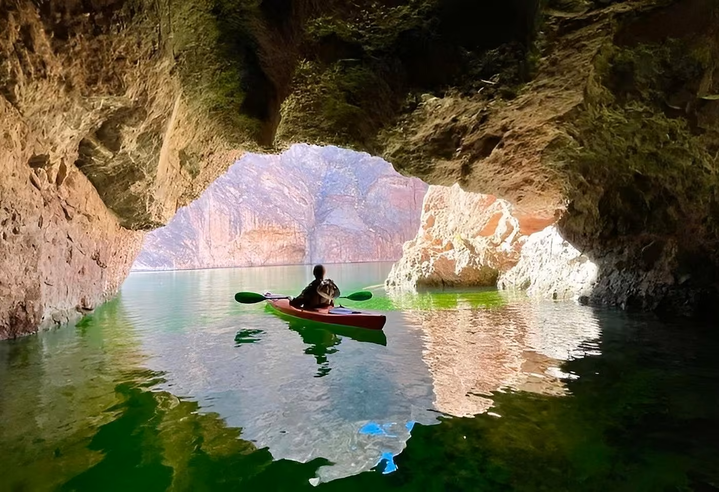 Kayaker paddling through Emerald Cave on glowing green water near Willow Beach on the Colorado River