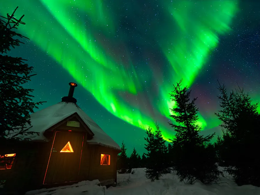 Northern lights illuminating a snowy landscape in Finnish Lapland