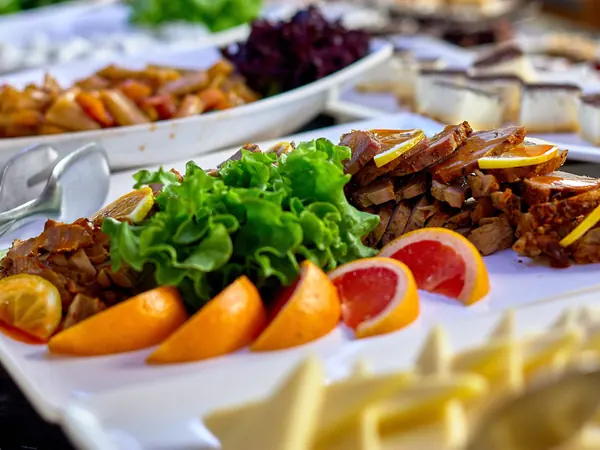 Roasted meat platter with fresh salad and citrus slices