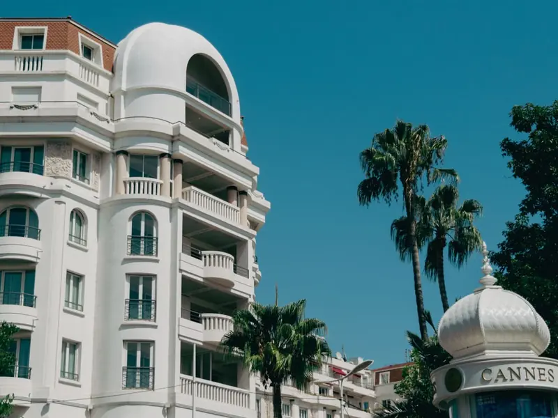 Elegant white building, palm trees and Cannes sign on the French Riviera