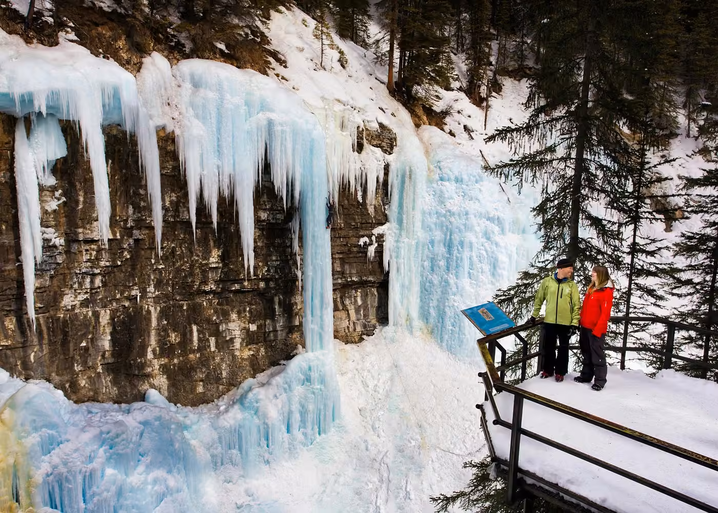 Visitors admiring spectacular frozen waterfalls and blue ice formations at Johnston Canyon in Banff National Park