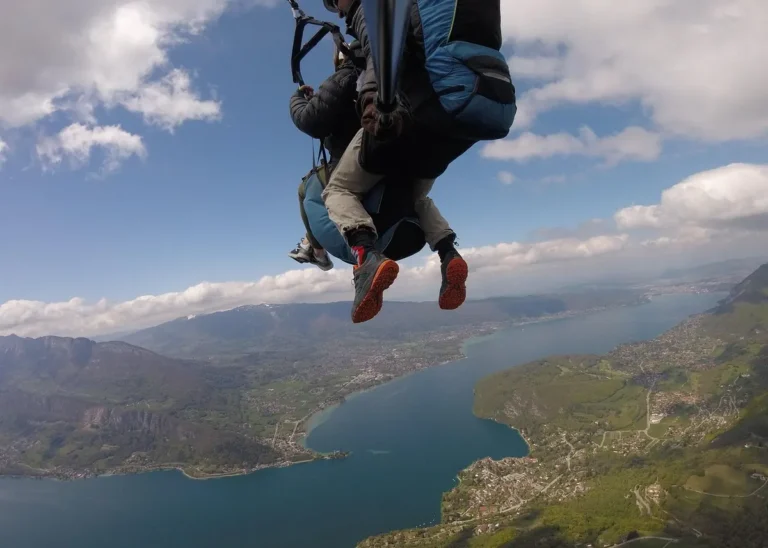 Tandem paragliding flight above Lake Annecy with panoramic views of the turquoise lake and surrounding French Alps