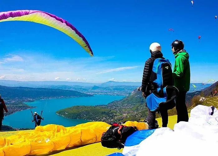 Tandem paragliding preparation on a mountain launch site overlooking Lake Annecy and the French Alps