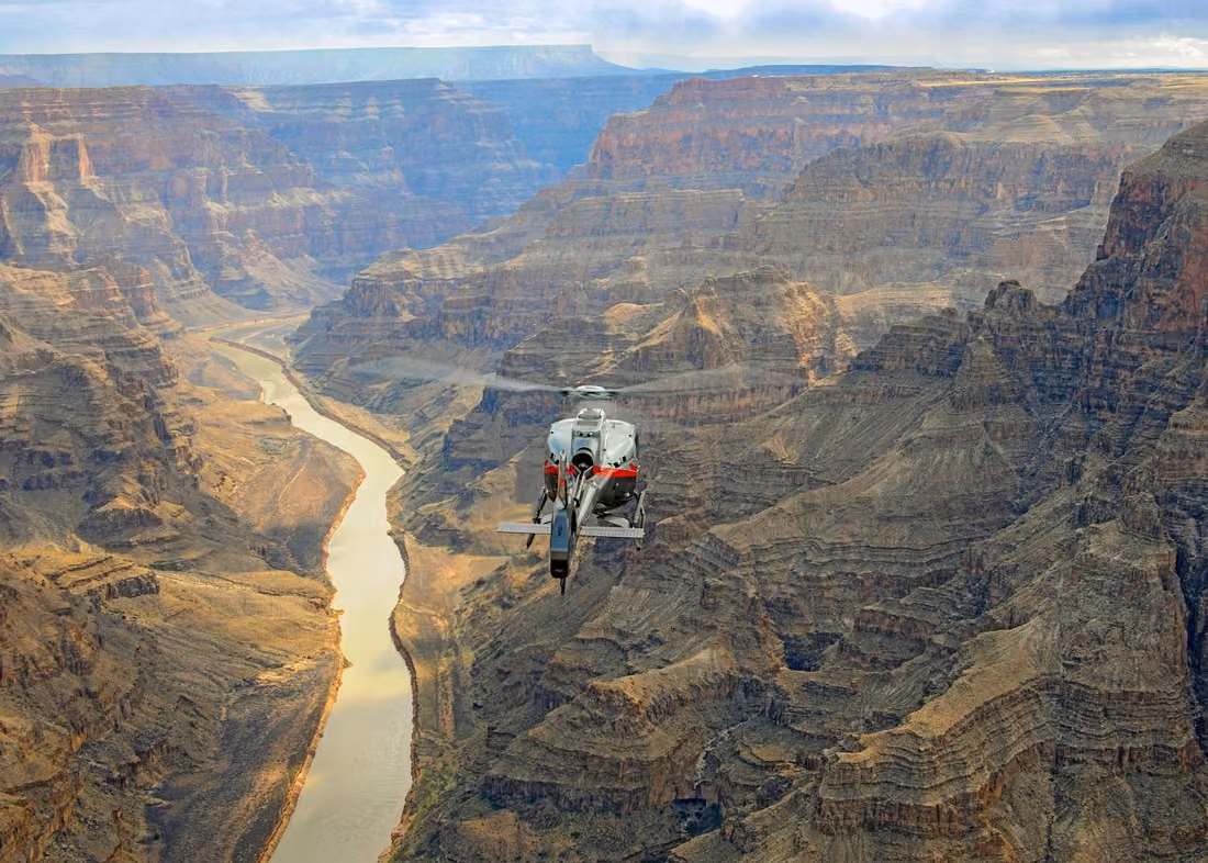 Helicopter flying over the Colorado River and dramatic Grand Canyon cliffs on a tour from Las Vegas