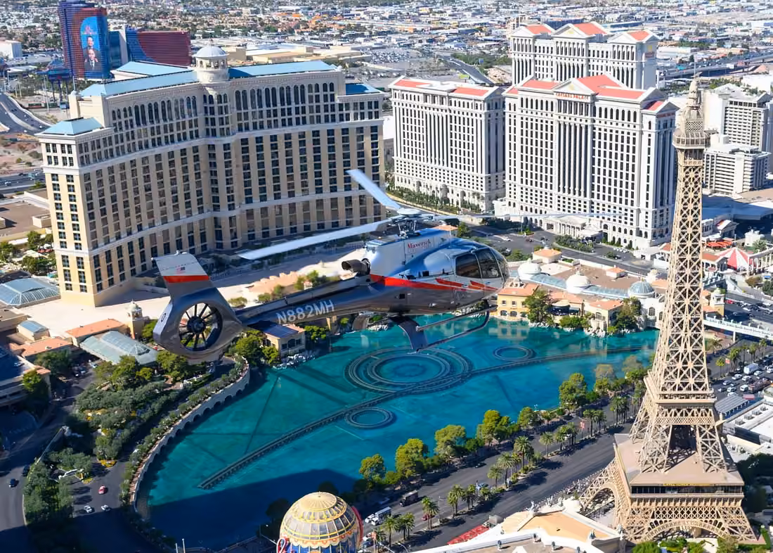 Maverick helicopter flying over the Las Vegas Strip with Bellagio fountains, Caesars Palace and the Eiffel Tower