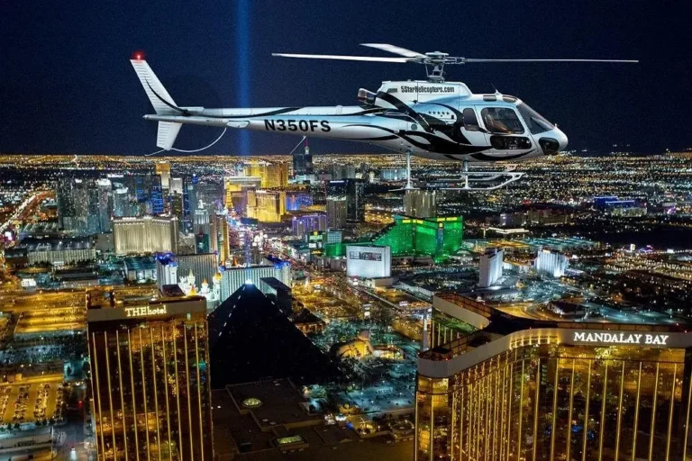 Helicopter flying above the illuminated Las Vegas Strip and famous casino resorts at night