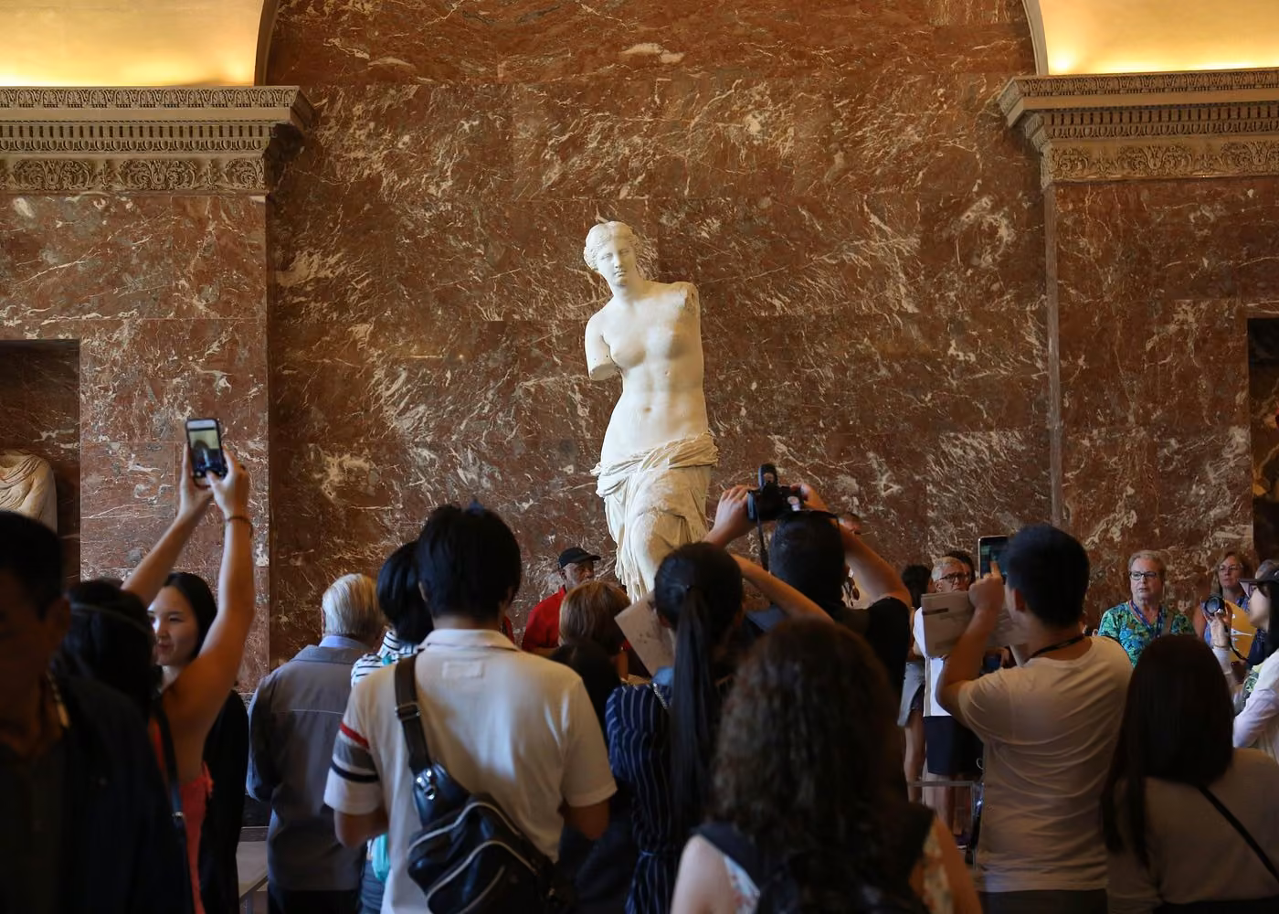 Venus de Milo sculpture surrounded by visitors at the Louvre Museum in Paris
