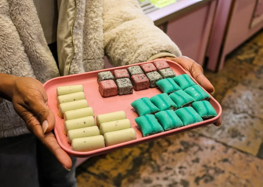 Assortment of colorful French sweets and confectionery presented on a pink tray during a food tasting