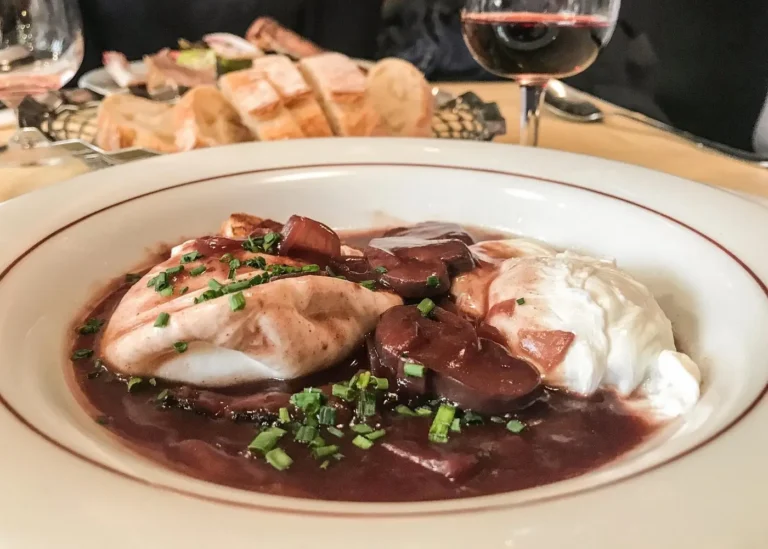 French poached eggs in rich red wine sauce with herbs, served with bread and a glass of red wine