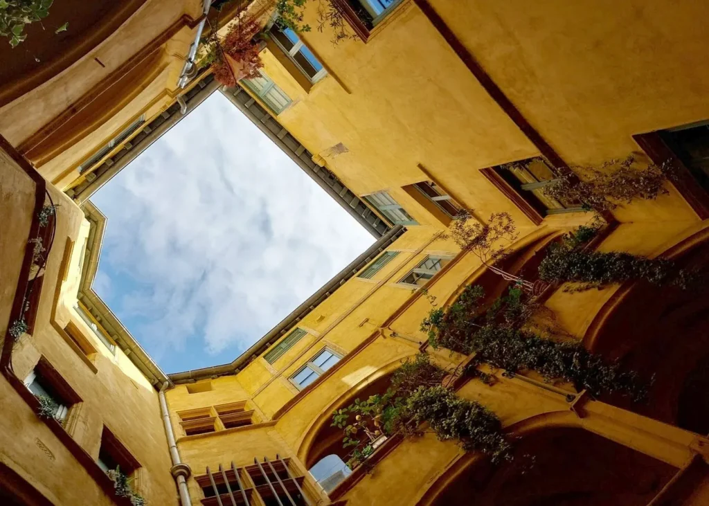 View looking up inside a historic Renaissance courtyard with yellow facades in Vieux Lyon