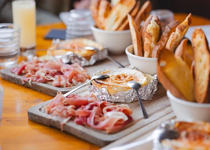 French food tasting with baked cheese, sliced cured ham and toasted bread on wooden serving boards