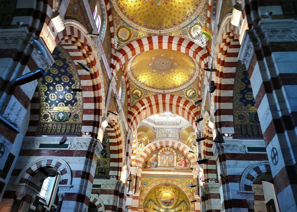 Ornate golden mosaics and striped arches inside Notre-Dame de la Garde Basilica in Marseille