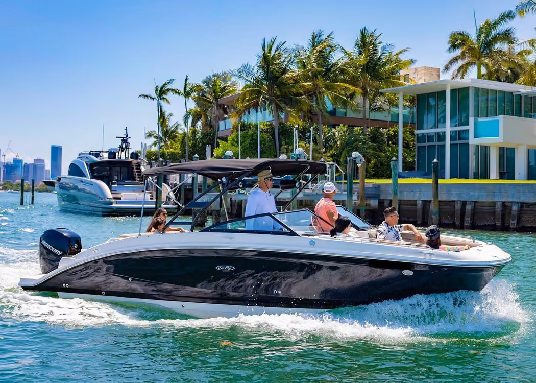 Private motorboat cruise with passengers passing luxury waterfront homes and palm trees in Miami Florida