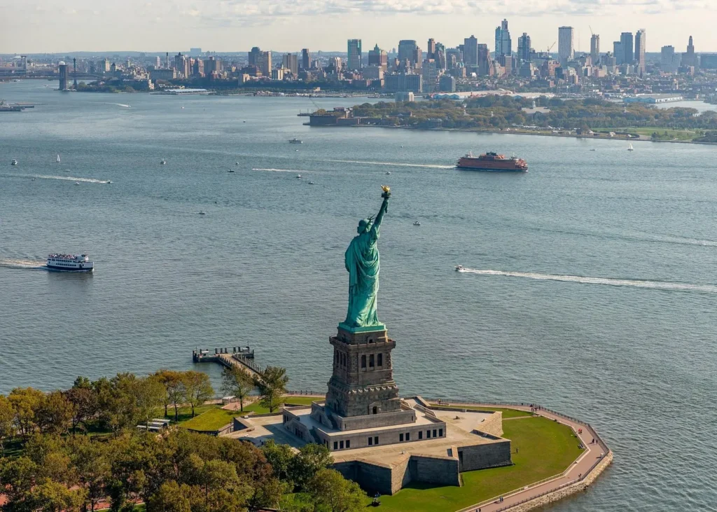 Aerial view of the Statue of Liberty on Liberty Island with New York Harbor and Brooklyn skyline in the background
