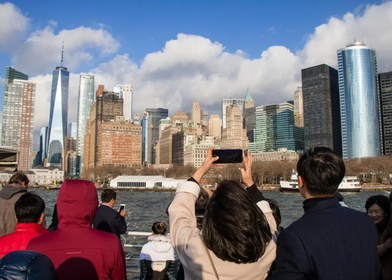 Tourists photographing the Lower Manhattan skyline and One World Trade Center from a ferry in New York Harbor