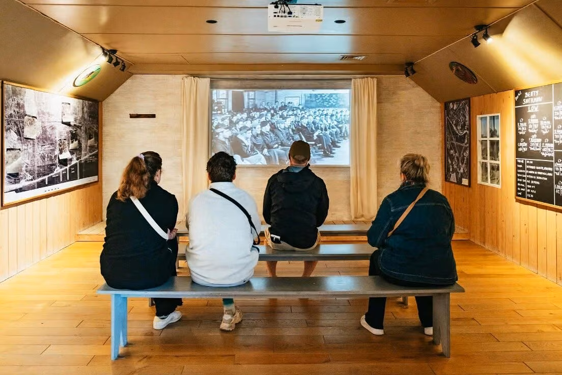 Visitors watching a historical World War II film inside a Normandy D-Day museum