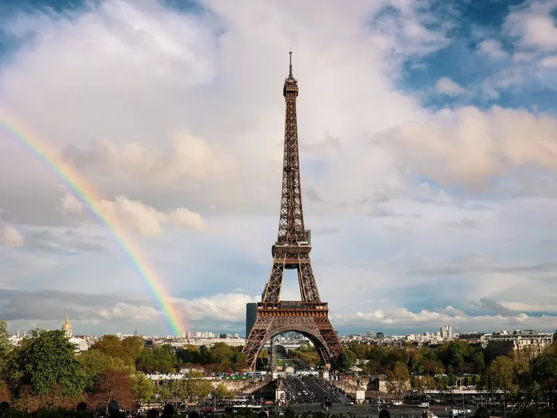 Eiffel Tower in Paris beneath a rainbow and dramatic cloudy sky