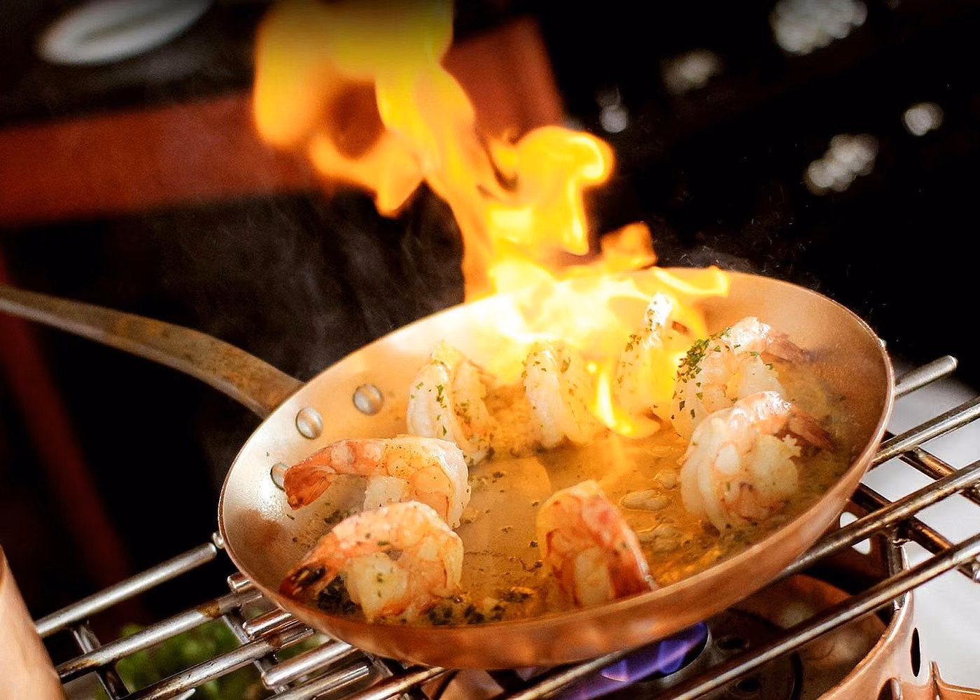 Flambéed shrimp cooking in a pan during a gourmet dining experience