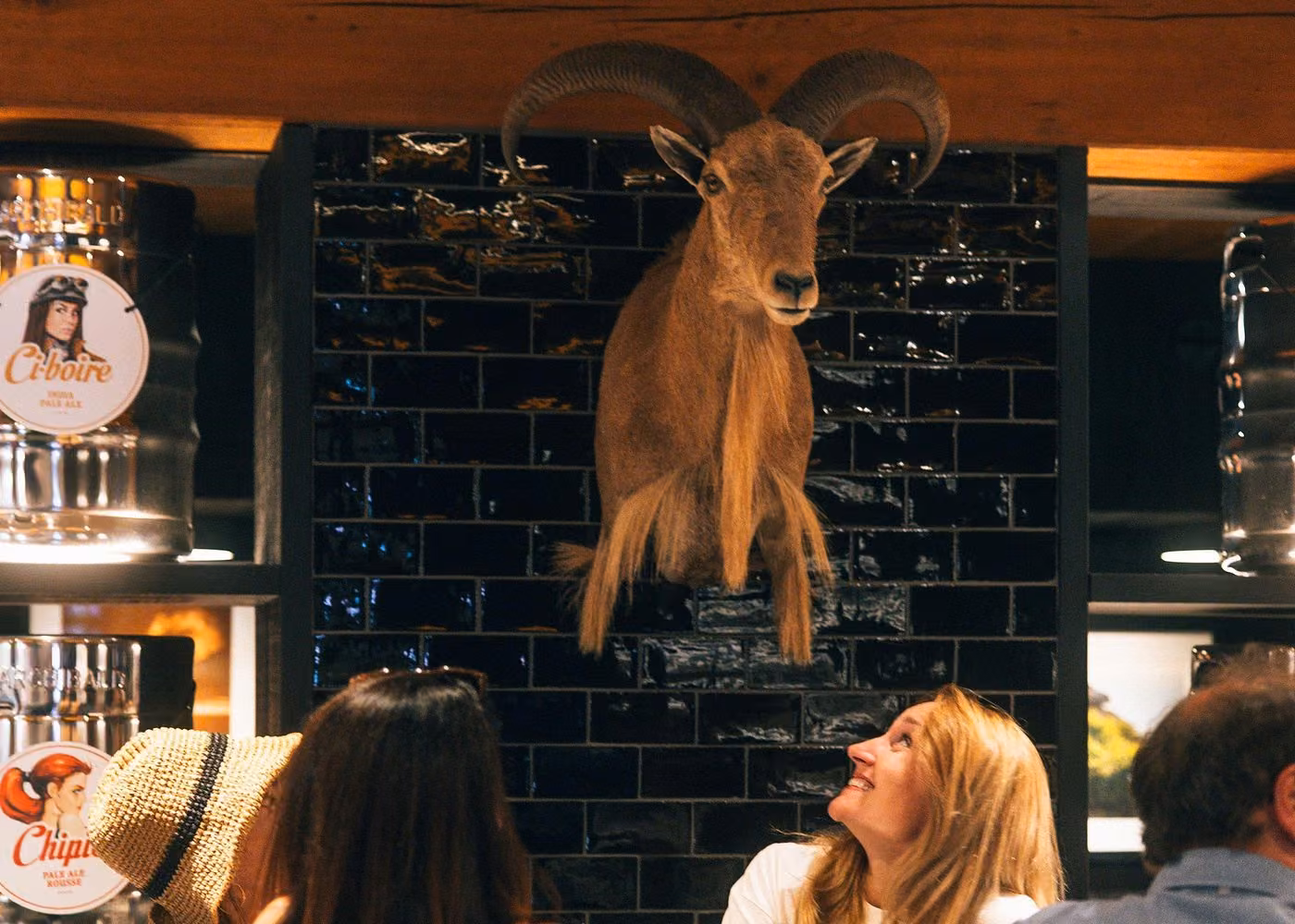 Guests inside a Quebec City restaurant with rustic decor and a mounted ram head