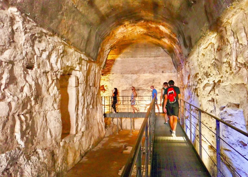 Visitors walking through an ancient stone passageway in the underground area of the Colosseum in Rome