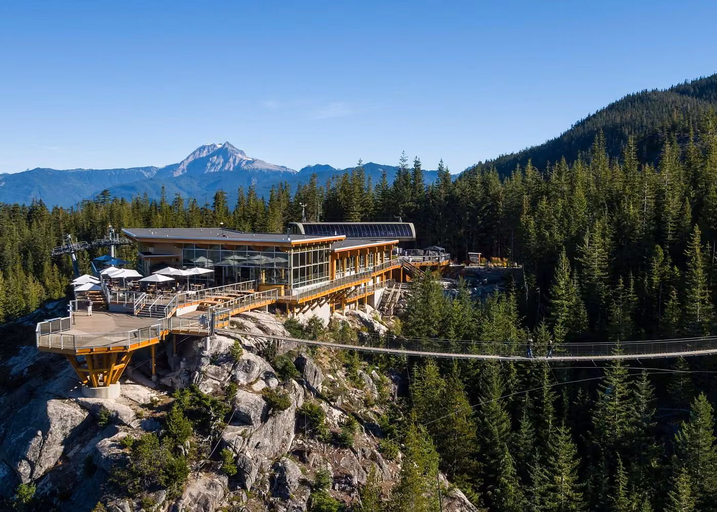 Sea to Sky Gondola summit lodge and Sky Pilot Suspension Bridge surrounded by forested mountains near Squamish