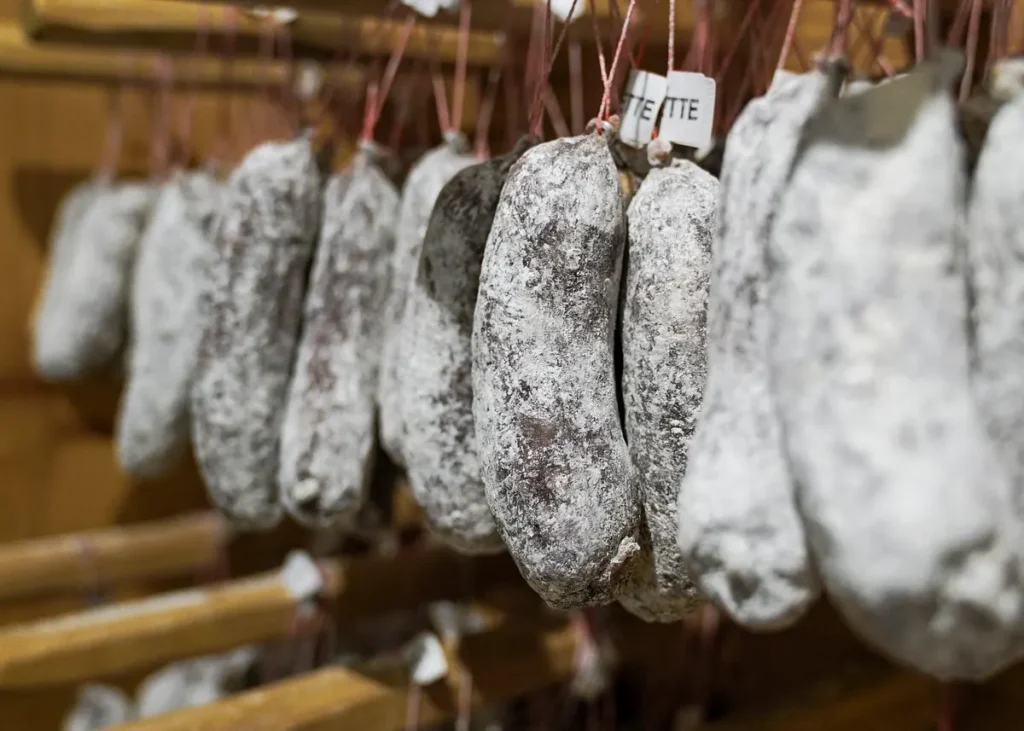 Traditional dry-cured sausages hanging in a charcuterie shop, illustrating Alsatian food traditions