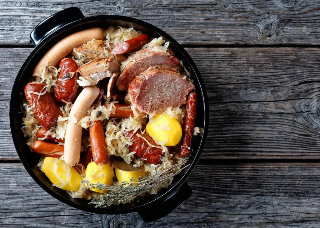 Traditional Alsatian choucroute garnie with assorted sausages, pork, sauerkraut and potatoes in a black serving dish