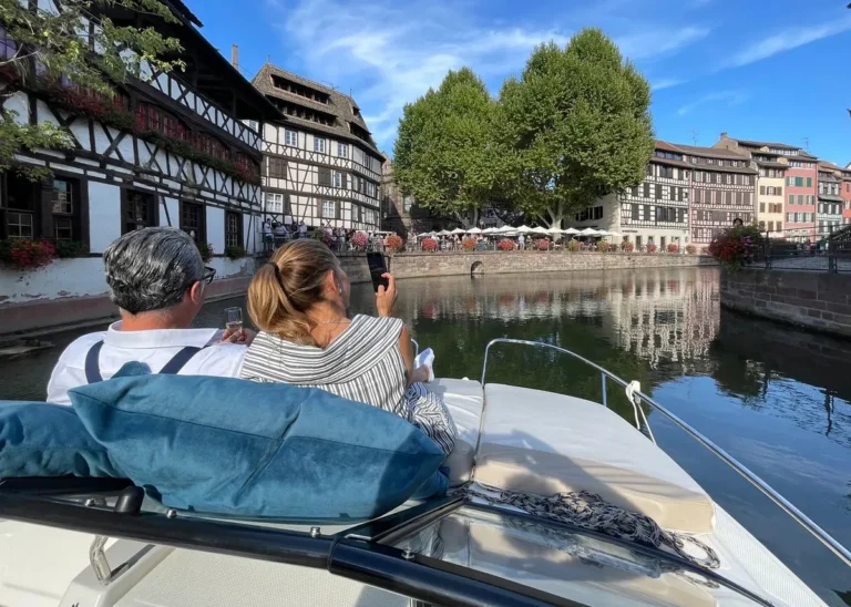 Passengers relaxing on a private boat beside the half-timbered houses of Petite France in Strasbourg