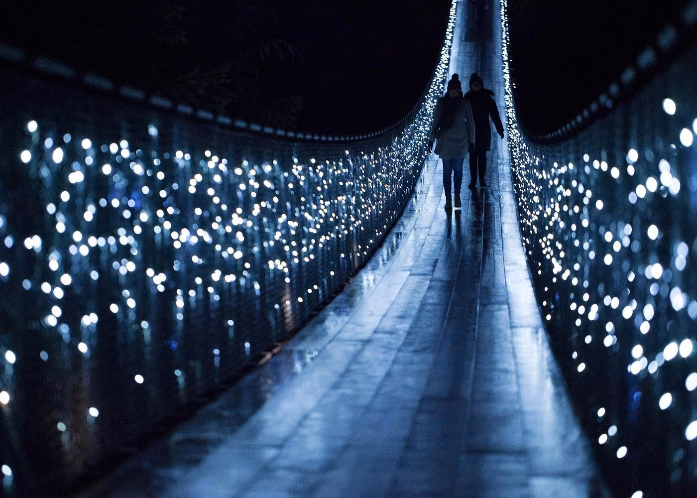 Visitors crossing the illuminated Capilano Suspension Bridge at night during Canyon Lights in North Vancouver