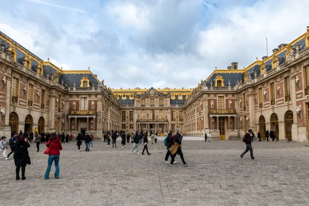 Visitors walking through the Royal Courtyard of the Palace of Versailles in France