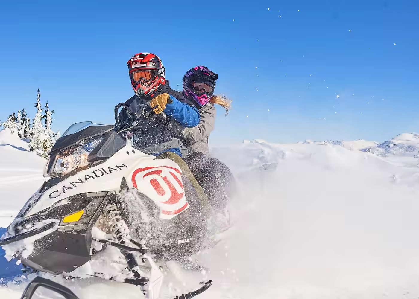 Two riders enjoying a snowmobile adventure in the snowy mountains of Whistler, British Columbia